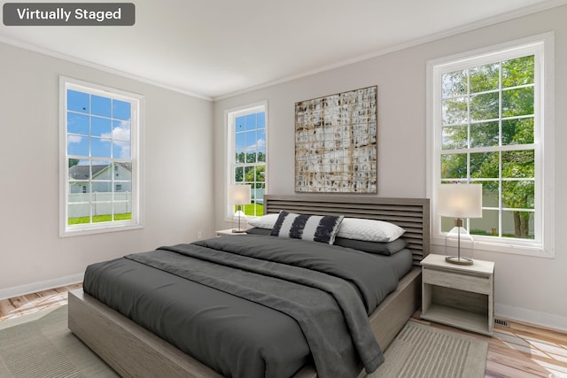 bedroom featuring light wood-type flooring and crown molding