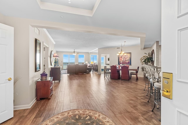 living room with dark hardwood / wood-style flooring and ceiling fan with notable chandelier