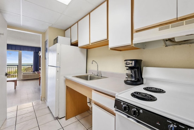 kitchen featuring a paneled ceiling, white appliances, sink, light tile patterned floors, and white cabinetry