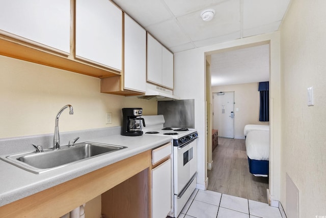 kitchen featuring a paneled ceiling, light hardwood / wood-style flooring, sink, white range with electric stovetop, and white cabinetry