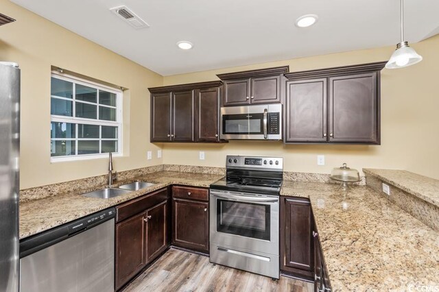 kitchen with appliances with stainless steel finishes, light hardwood / wood-style floors, sink, and dark brown cabinets