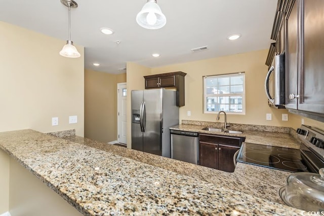 kitchen featuring appliances with stainless steel finishes, decorative light fixtures, light stone counters, and dark brown cabinets