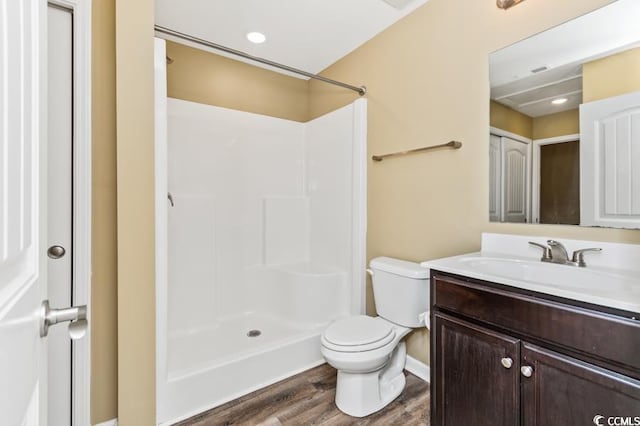 bathroom with toilet, hardwood / wood-style flooring, walk in shower, and vanity