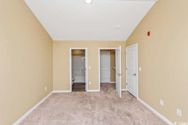 unfurnished bedroom featuring carpet, vaulted ceiling, and connected bathroom