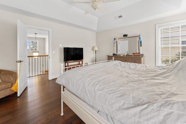 bedroom with ceiling fan, dark hardwood / wood-style floors, and a tray ceiling