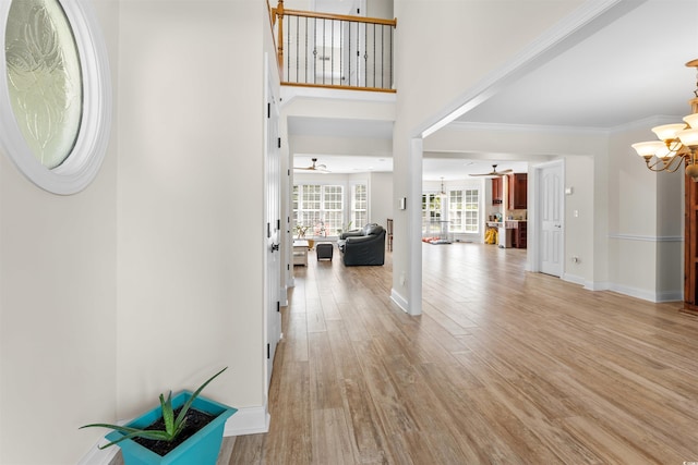 foyer entrance with ceiling fan with notable chandelier, light hardwood / wood-style floors, and crown molding