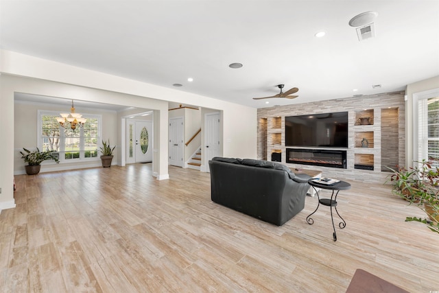 living room with a large fireplace, a healthy amount of sunlight, ceiling fan with notable chandelier, and light hardwood / wood-style floors