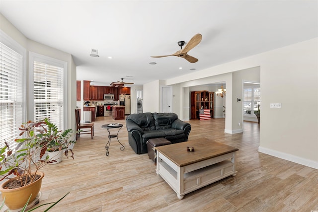 living room with ceiling fan with notable chandelier and light wood-type flooring