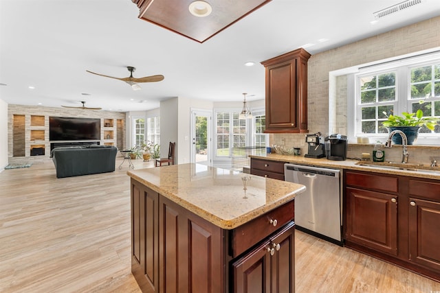 kitchen with dishwasher, sink, light stone counters, light hardwood / wood-style floors, and a kitchen island