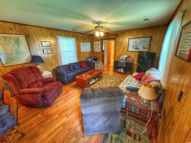 living room featuring a ceiling fan, visible vents, a textured ceiling, and wood finished floors