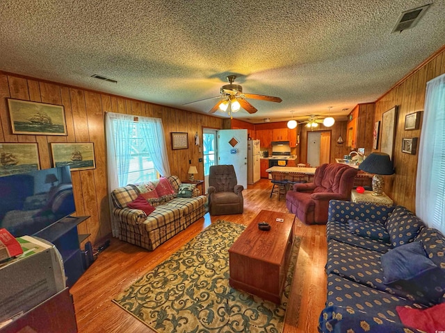 living room featuring a textured ceiling, light wood finished floors, and visible vents