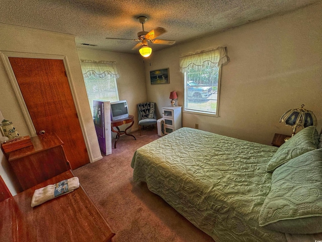 bedroom with carpet floors, visible vents, a textured ceiling, and a ceiling fan