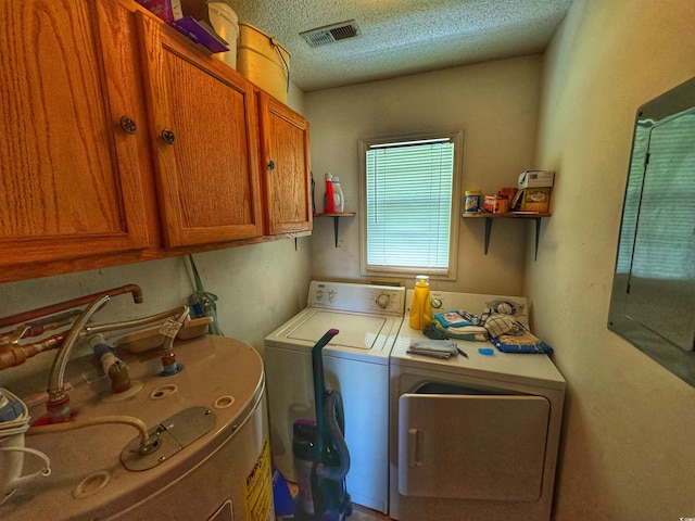 laundry area with visible vents, separate washer and dryer, a textured ceiling, and cabinet space