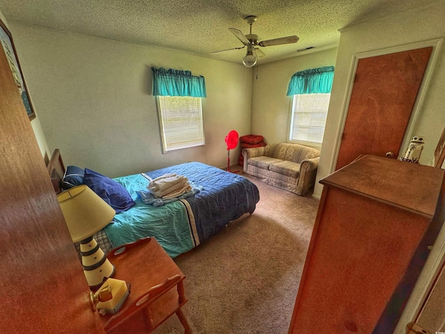 carpeted bedroom featuring ceiling fan, visible vents, and a textured ceiling