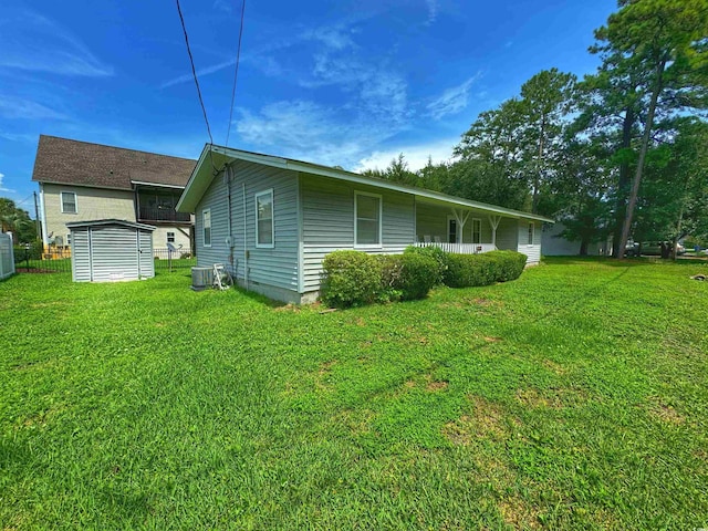 view of side of property with a storage shed, a yard, an outbuilding, and cooling unit