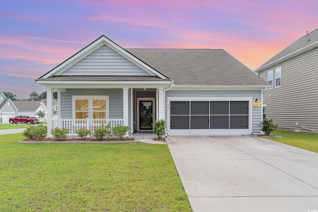 view of front of house featuring a porch, a garage, and a yard