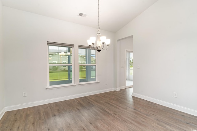 empty room with hardwood / wood-style floors, high vaulted ceiling, and an inviting chandelier