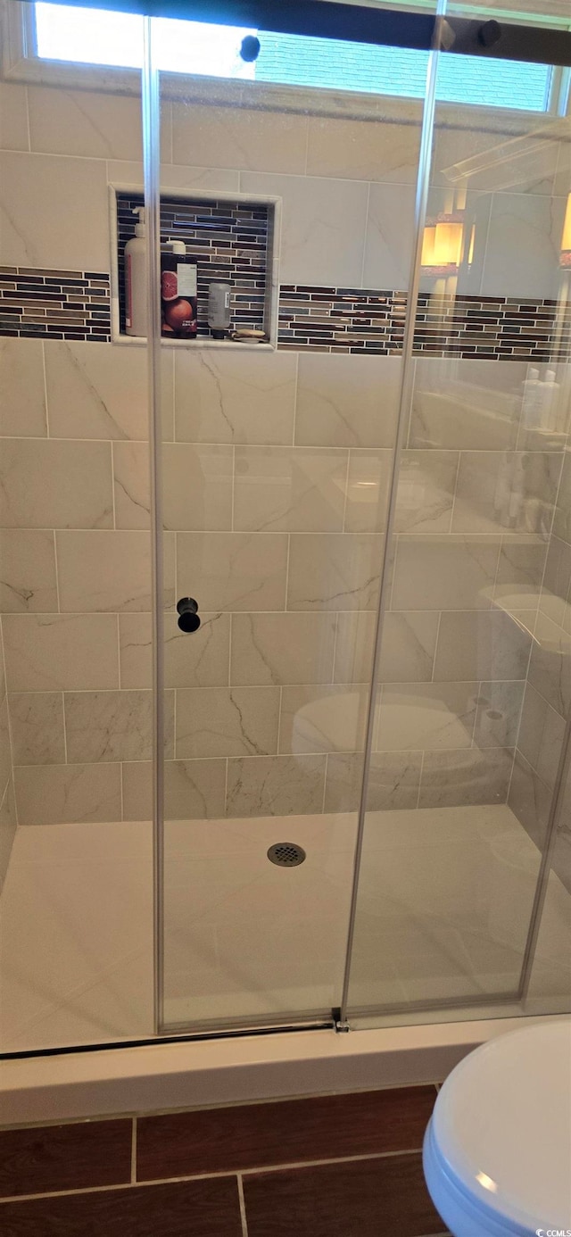 bathroom with a shower with shower door and toilet