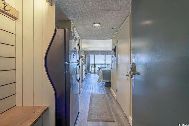 hallway with light hardwood / wood-style flooring and a textured ceiling