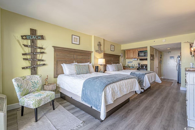 bedroom with hardwood / wood-style flooring and stainless steel refrigerator