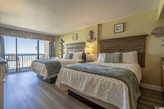 bedroom featuring dark hardwood / wood-style flooring, access to outside, and a water view