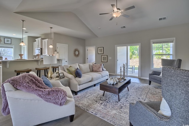 living room featuring ceiling fan, light wood-type flooring, and vaulted ceiling