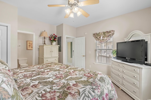 bedroom with ceiling fan, light colored carpet, and ensuite bathroom