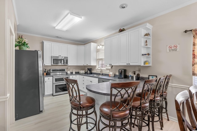 kitchen featuring sink, white cabinetry, kitchen peninsula, and appliances with stainless steel finishes