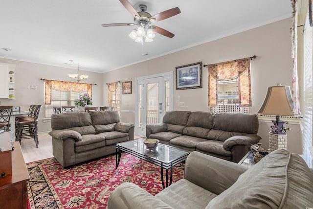 living room with ceiling fan with notable chandelier and ornamental molding