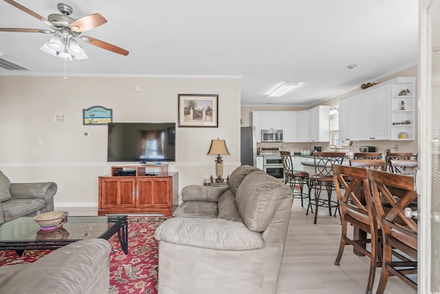 living room featuring crown molding, light hardwood / wood-style flooring, and ceiling fan