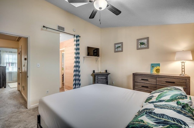 bedroom featuring light carpet, ensuite bath, a textured ceiling, and ceiling fan