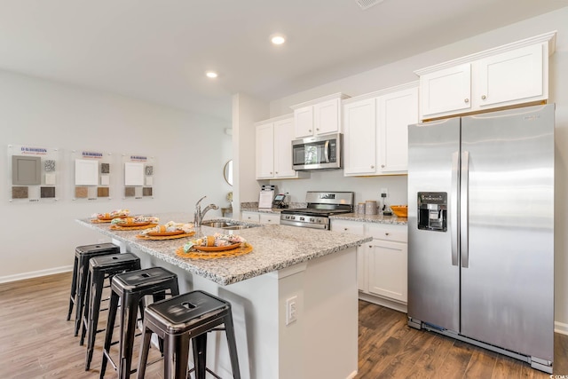 kitchen featuring white cabinetry, sink, stainless steel appliances, dark hardwood / wood-style floors, and a kitchen island with sink