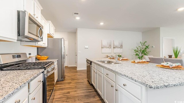 kitchen featuring stainless steel appliances, a kitchen island with sink, dark wood-type flooring, sink, and white cabinets