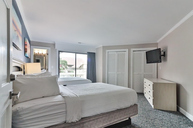 bedroom featuring ornamental molding, dark colored carpet, and two closets