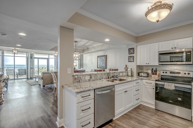 kitchen featuring appliances with stainless steel finishes, light hardwood / wood-style flooring, kitchen peninsula, and sink