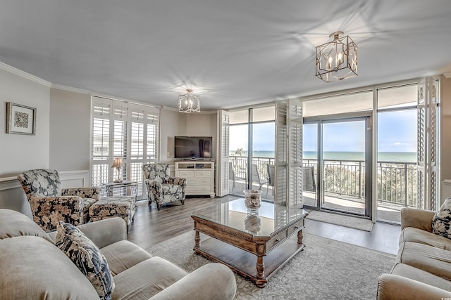 living area featuring wainscoting, ornamental molding, wood finished floors, an inviting chandelier, and a wall of windows