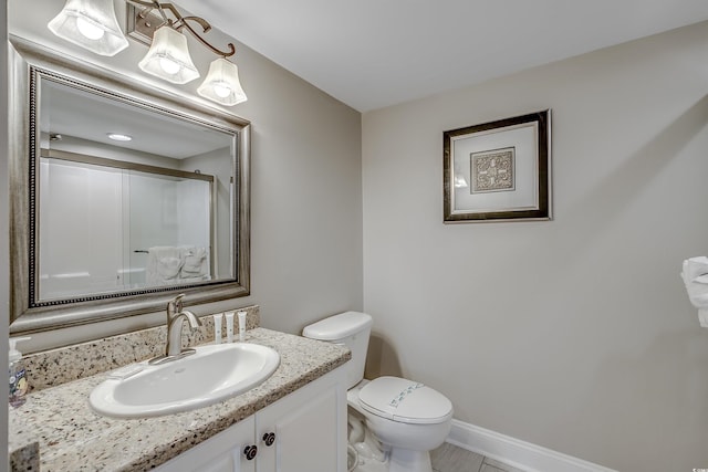 bathroom with baseboards, a shower with shower door, vanity, and toilet