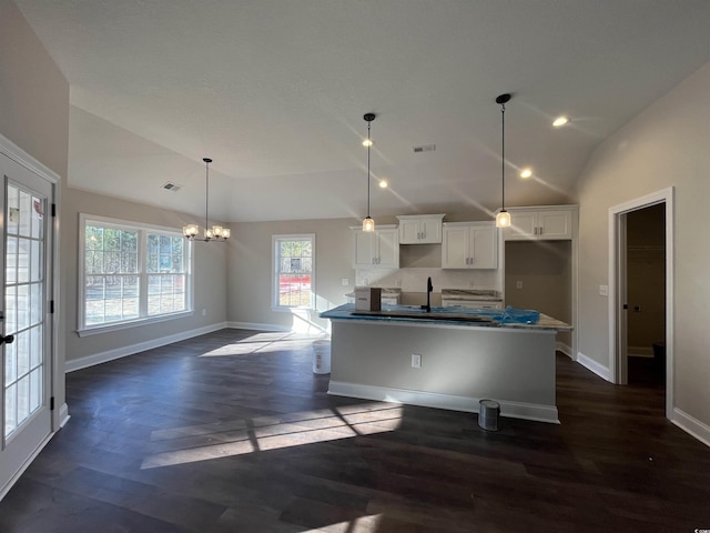 kitchen with lofted ceiling, white cabinetry, decorative light fixtures, dark hardwood / wood-style flooring, and a kitchen island with sink