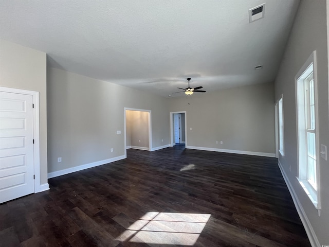 unfurnished room featuring ceiling fan, plenty of natural light, dark hardwood / wood-style floors, and a textured ceiling