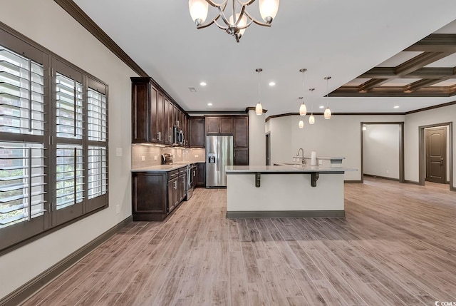 kitchen with a center island with sink, pendant lighting, stainless steel appliances, and light wood-type flooring