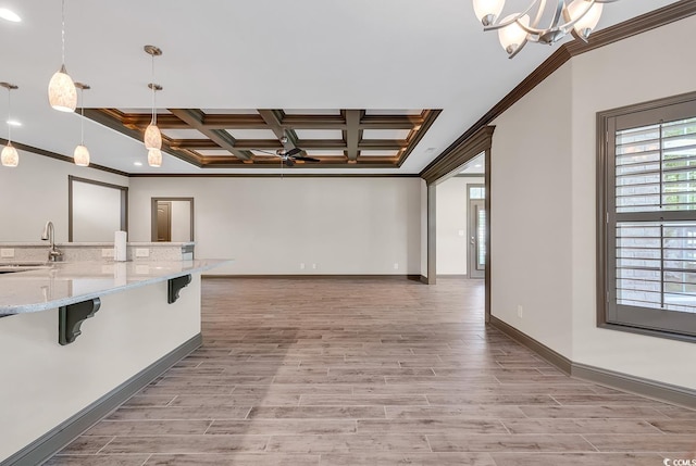 kitchen featuring light stone countertops, hanging light fixtures, light hardwood / wood-style floors, coffered ceiling, and a breakfast bar area