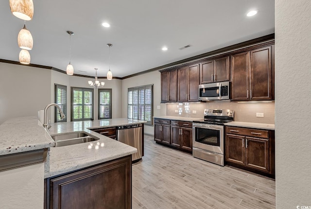 kitchen featuring dark brown cabinets, appliances with stainless steel finishes, light wood-type flooring, pendant lighting, and sink