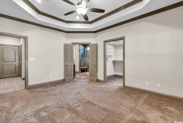 unfurnished bedroom with a spacious closet, crown molding, and ceiling fan