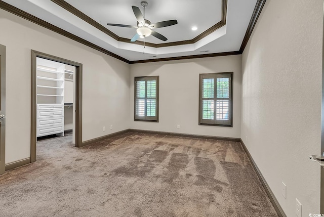 unfurnished bedroom featuring ceiling fan, crown molding, carpet, and a walk in closet