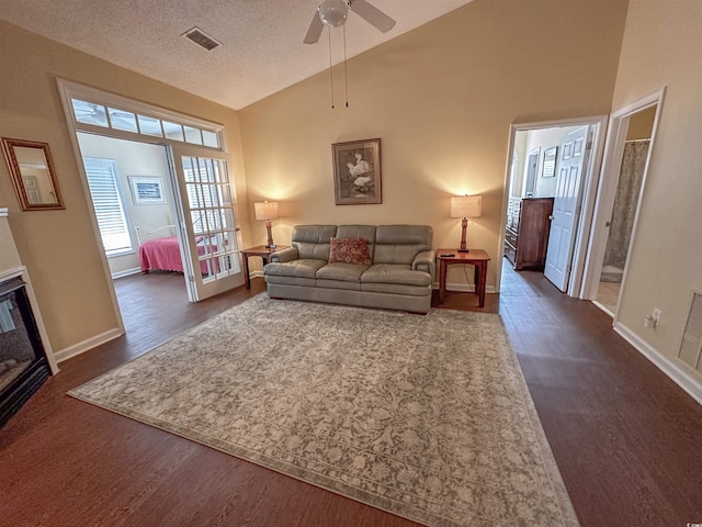 living room featuring ceiling fan, a textured ceiling, dark hardwood / wood-style floors, and high vaulted ceiling