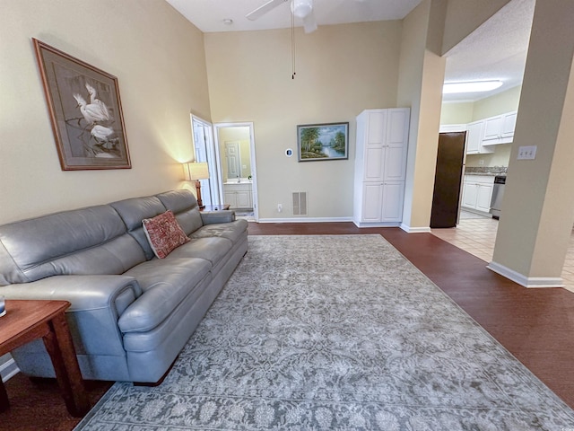 living room featuring a high ceiling, ceiling fan, and hardwood / wood-style flooring