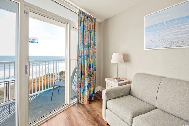 sitting room featuring a water view, baseboards, a beach view, and wood finished floors