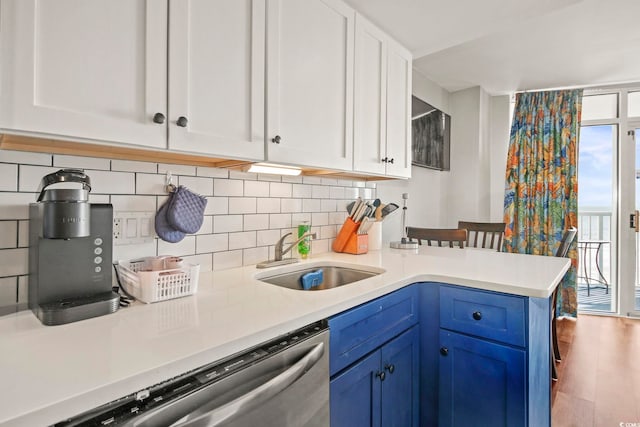 kitchen featuring blue cabinetry, tasteful backsplash, light countertops, a sink, and dishwasher