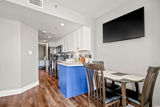 kitchen featuring stainless steel appliances, wood finished floors, white cabinetry, visible vents, and decorative backsplash