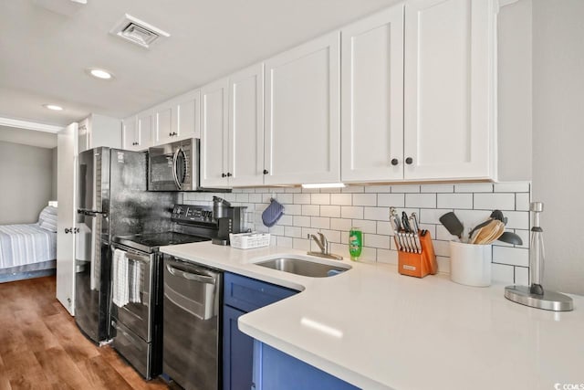 kitchen with visible vents, white cabinets, appliances with stainless steel finishes, blue cabinetry, and a sink